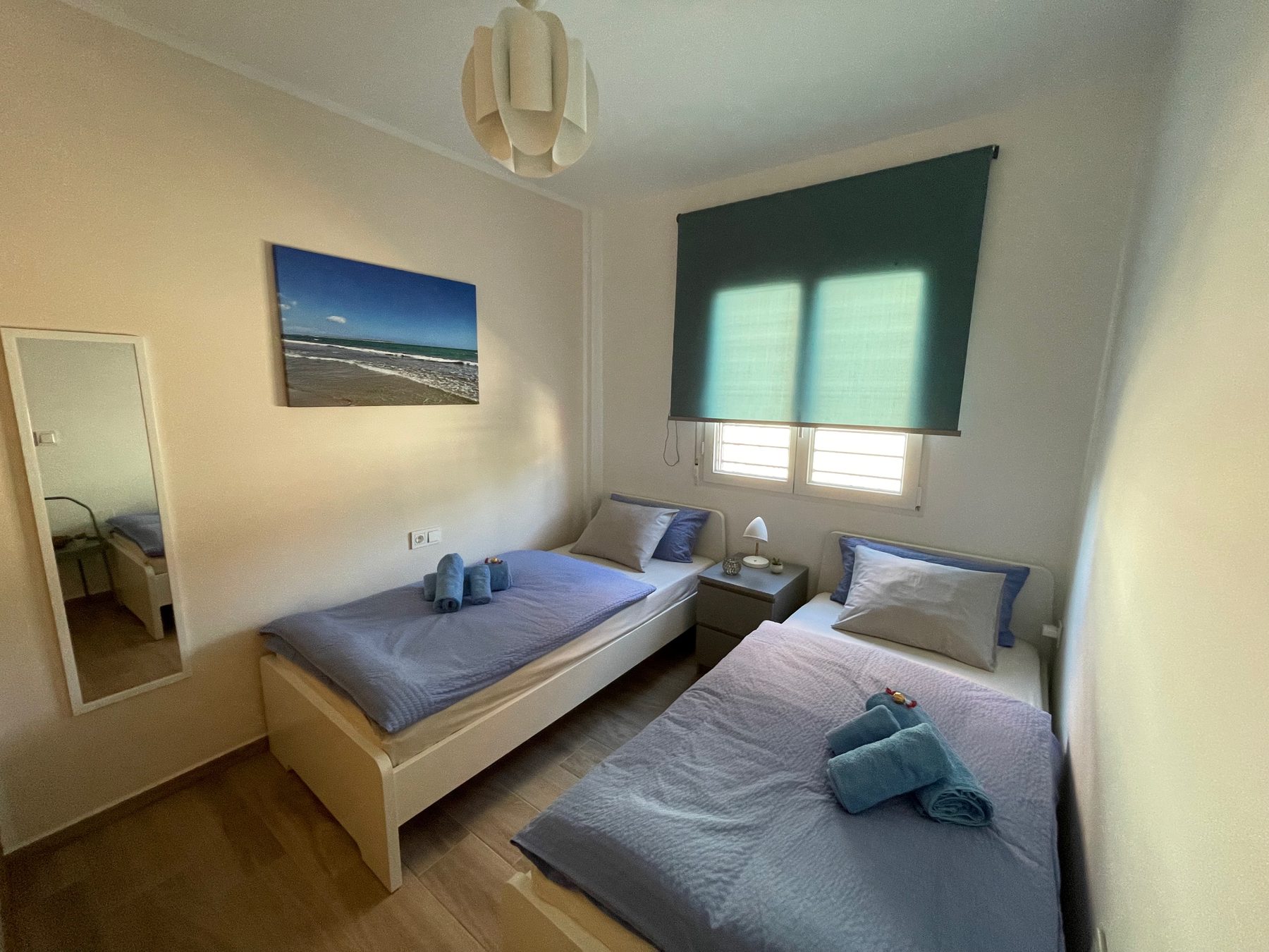Gaestezimmer mit zwei Betten und Meeresbild an der Wand