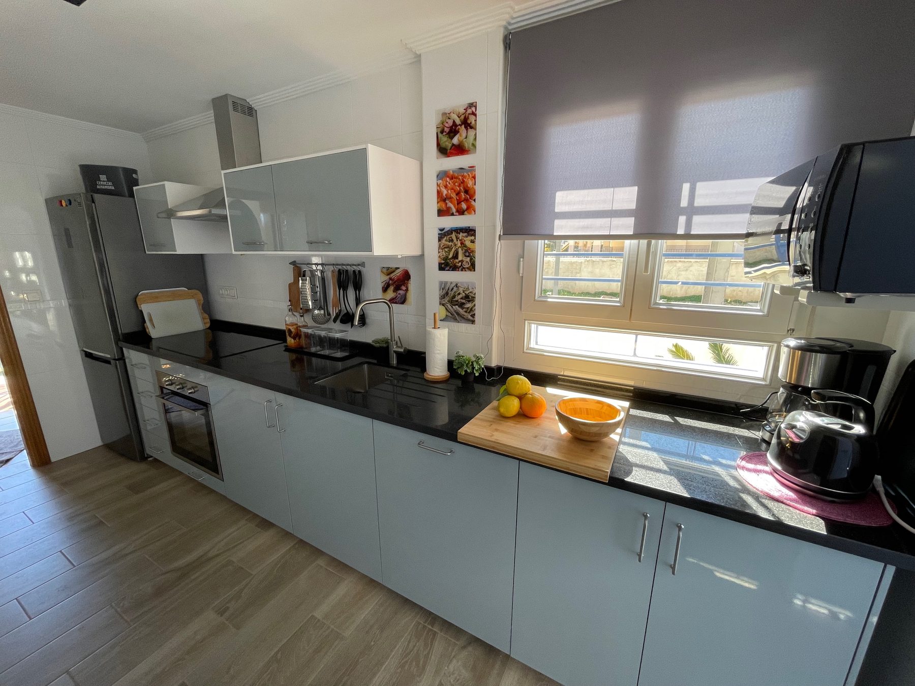 Moderne helle Kueche mit schwarzer Arbeitsplatte und grossem Fenster