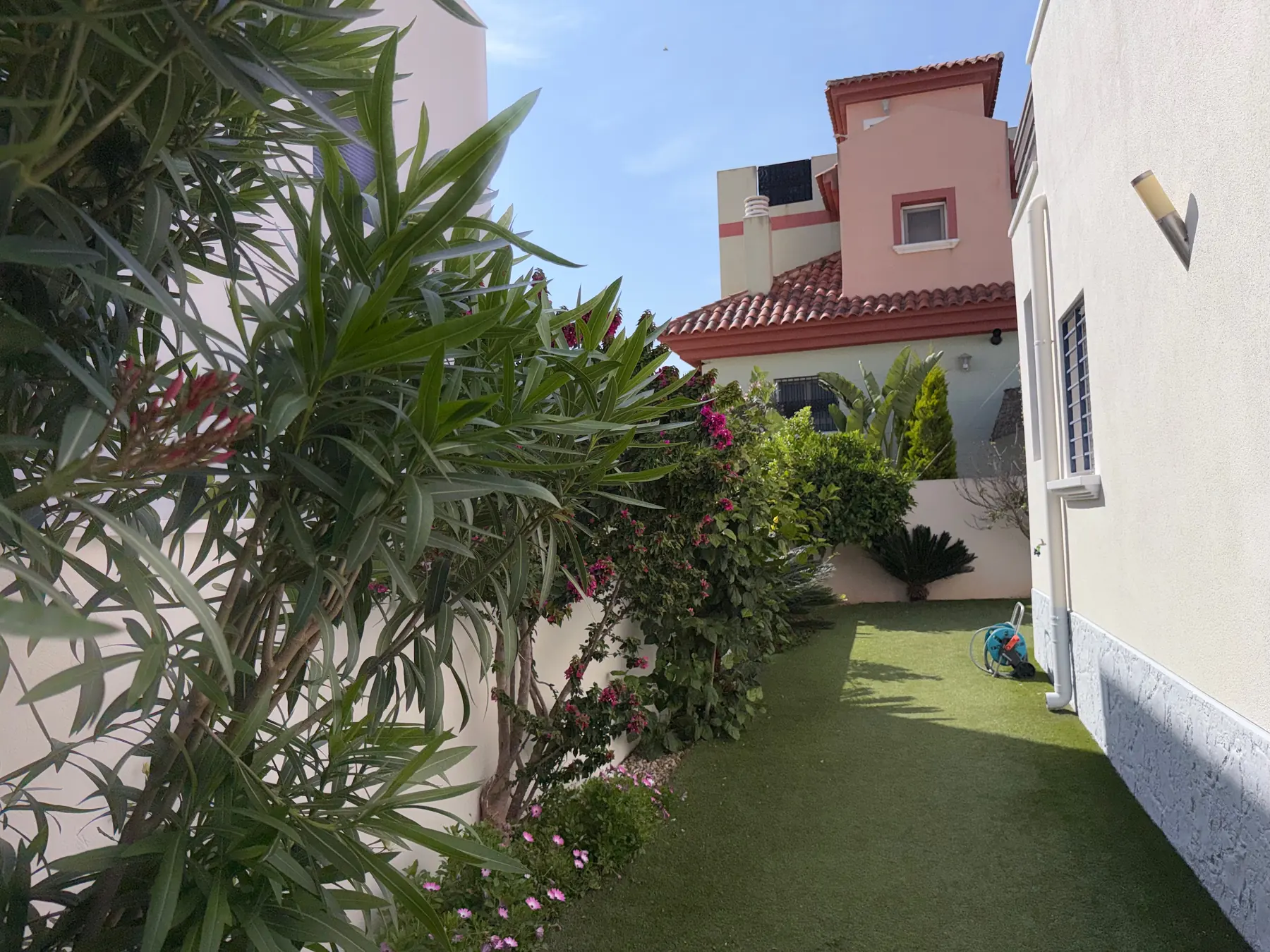 Mediterraner Garten mit Blueten und sonnigem Seitenbereich