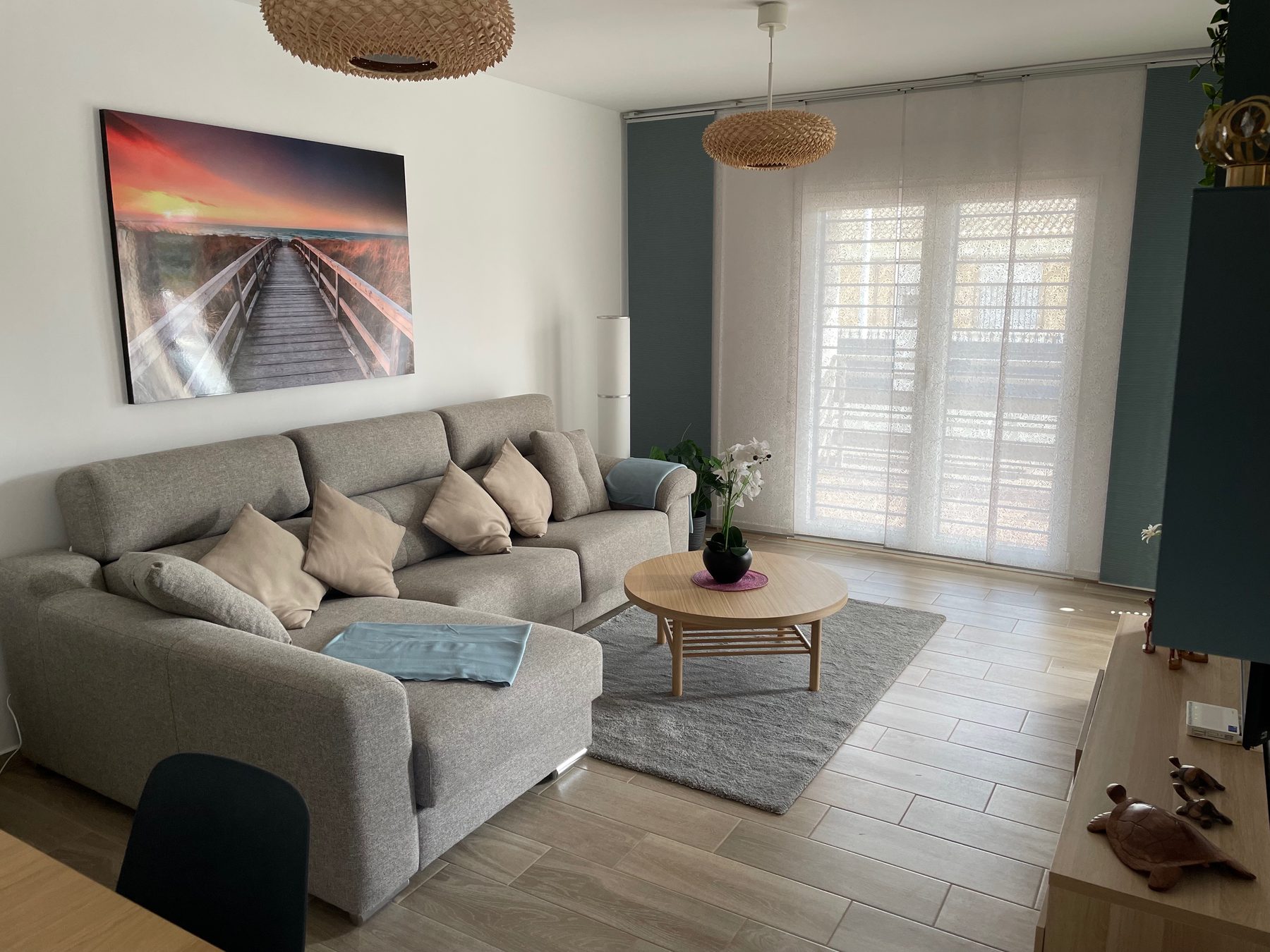 Wohnzimmer mit grauem Sofa, grossem Fenster und hellem Boden